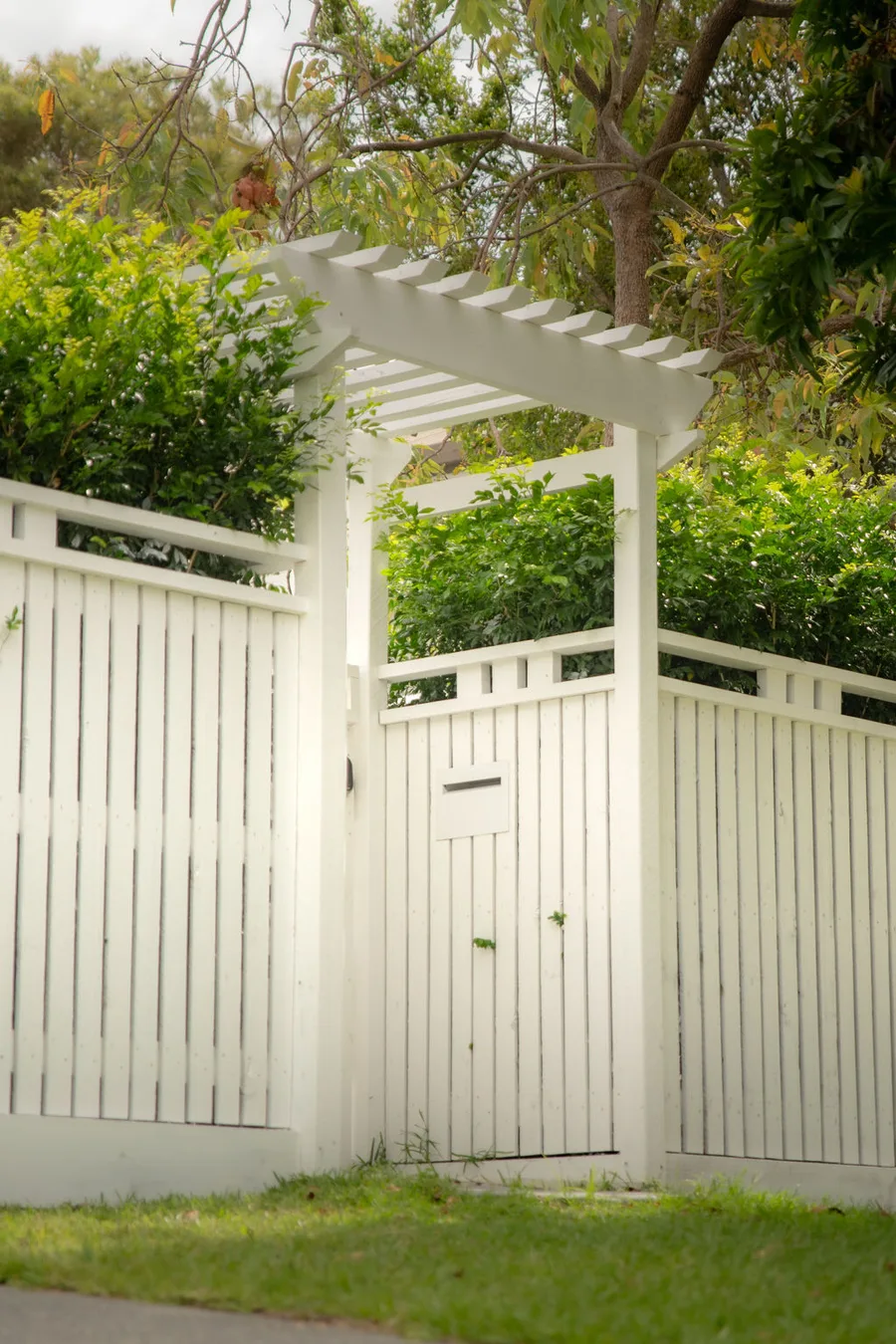 Pedestrian slatted gate with white pergola arch — heritage-residential entry detail.