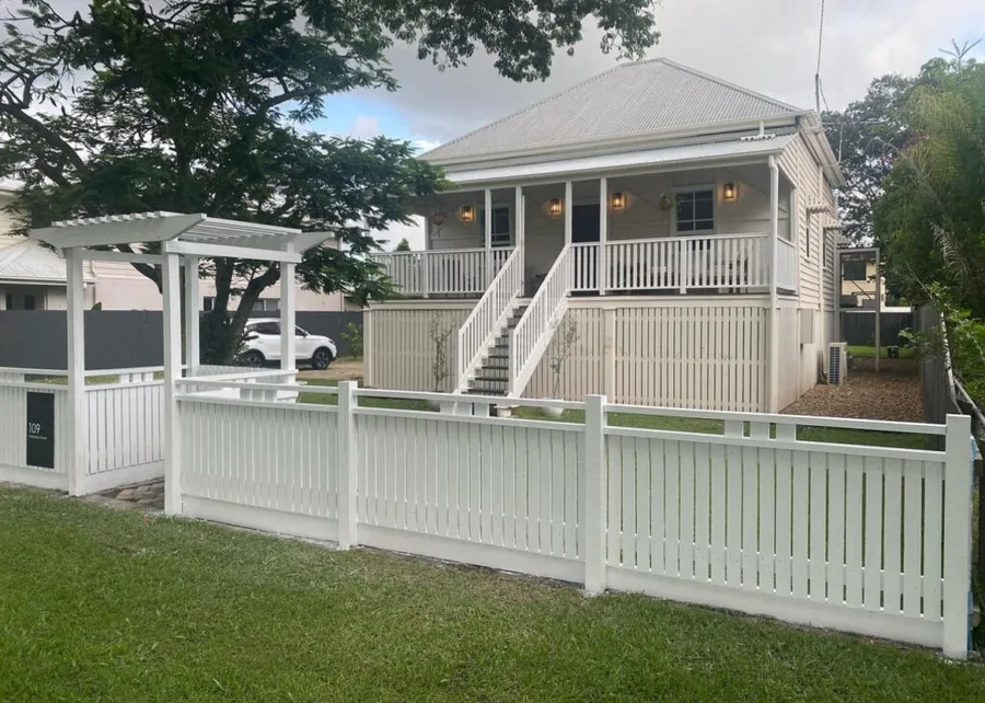 White picket front fence with pergola entry — restored Queenslander, full property frontage.